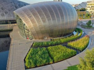 Portfolio image, Glasgow Science Centre , metal domed building, surrounded by water, walkways, aquatic plants